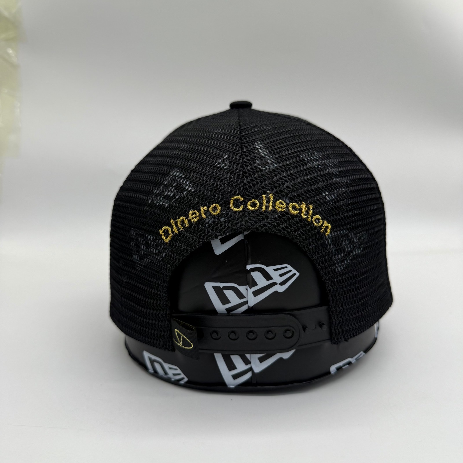 Matte noir trucker back with gold Dinero Collection arch embroidery