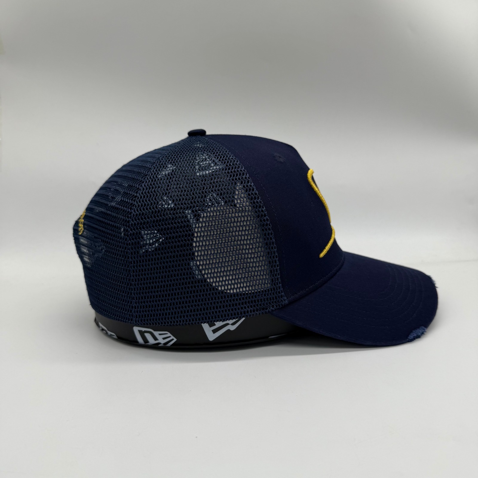 Midnight navy Dinero trucker cap side profile showing mesh